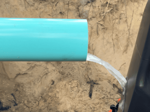 Repaired PVC water line being pressure tested in an open trench